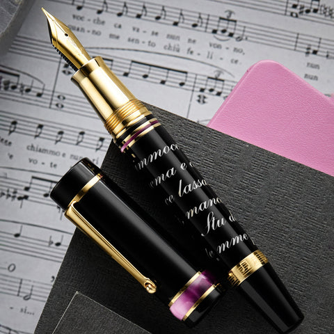Delta Italian Songs fountain pen with a gold nib beside sheet music and a pink notebook