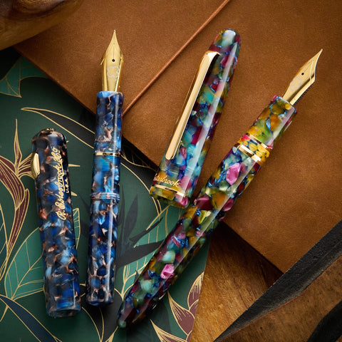 Esterbrook fountain pens with marbled blue bodies and gold nibs on a brown textured surface.