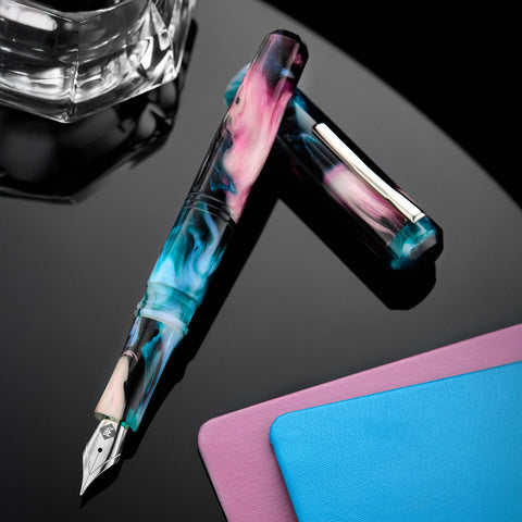 Close up of Franklin-Christoph fountain pens with swirled pink blue and teal resin barrels on a dark background