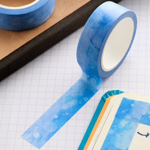 Close up of blue washi tape rolls and a strip on a grid paper background