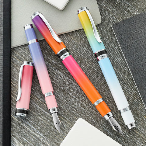 Monteverde Innova fountain pens in colorful gradients laid out on a wooden desk