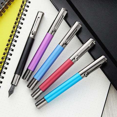 Monteverde Ritma pens in bold teal purple and blue with metal caps resting on a white dotted notebook