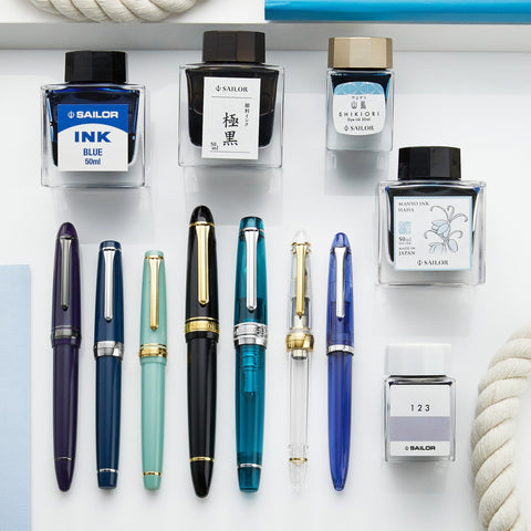 Sailor fountain pens in blue and teal with gold trims displayed on a white shelf