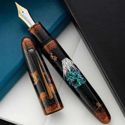 Close up of two TACCIA fountain pens with dark bodies copper speckle patterns and a gold nib