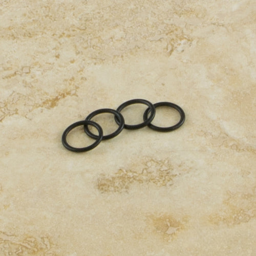 Four black rubber o-rings on a beige marble surface