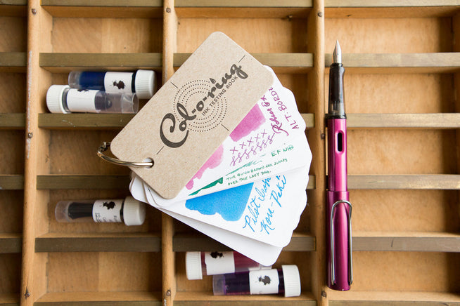Col-O-Ring Ink Testing Book, ink samples, and LAMY AL-star on a wooden box
