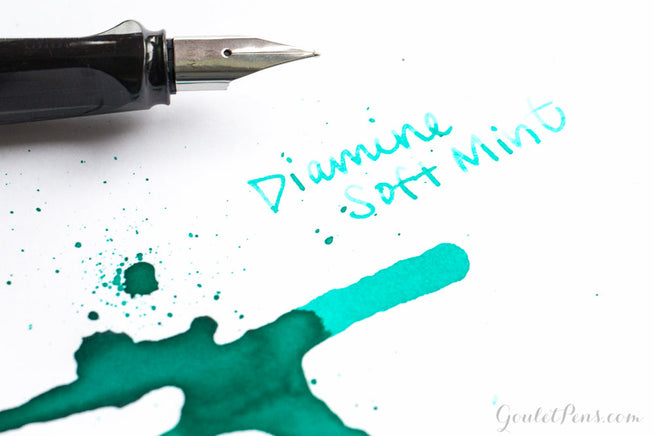 LAMY AL-star fountain pen with nib next to Diamine Soft Mint fountain pen ink splatter and writing