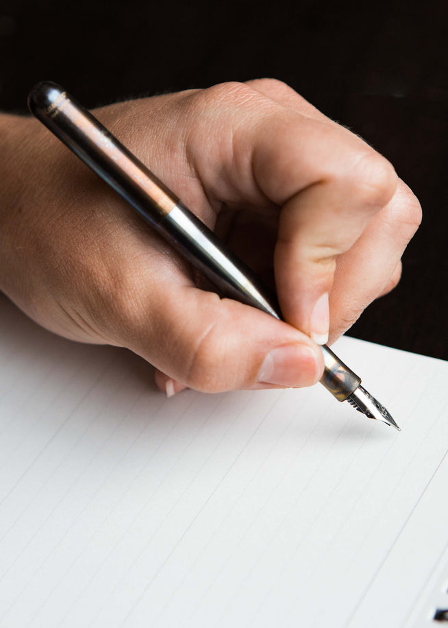 Left hand holding a Kaweco Liliput fountain pen