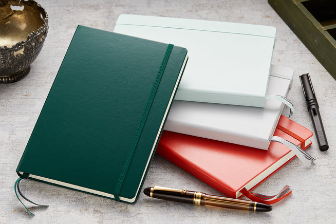 Leuchtturm1917 Notebooks stacked on top of each other with fountain pens in the background