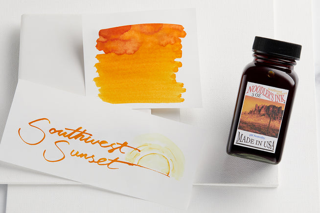 Bottle of Noodler's Southwest Sunset with swab and writing sample on white background