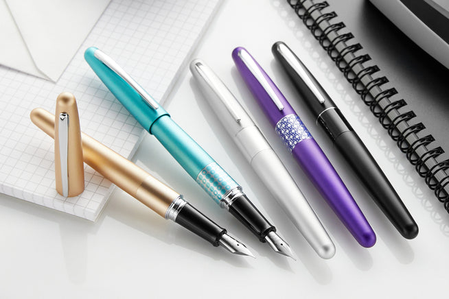 Black Pilot Metropolitan uncapped with assorted other colors capped on notebook