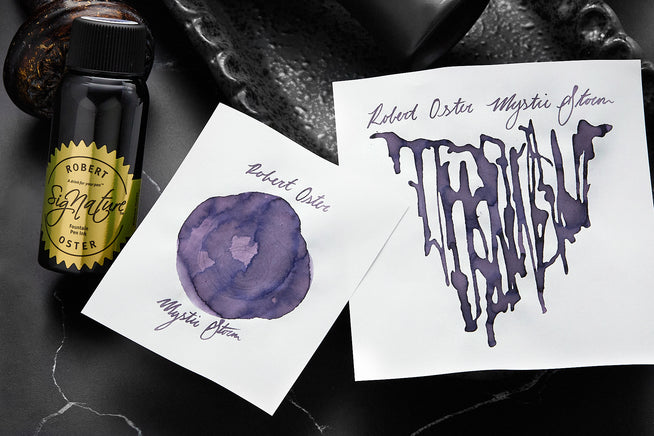 Robert Oster Mystic Storm fountain pen ink bottle, and samples on dark background