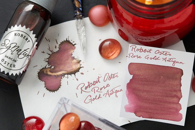 Writing samples of Robert Oster Rose Gold Antiqua on various white papers with ink splatters