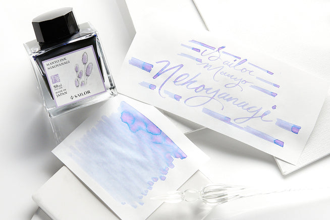 Sailor Manyo Nekoyanagi fountain pen ink bottle with writing samples on white paper on white background