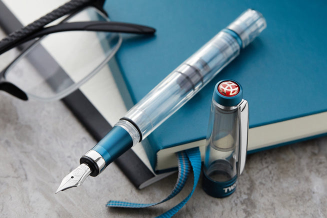 TWSBI 580ALR in Prussian Blue on a blue notebook with eye glasses to the side