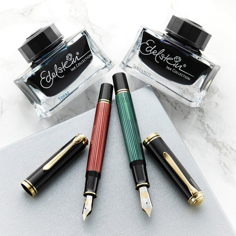 Two red and green fountain pens with two bottles of ink