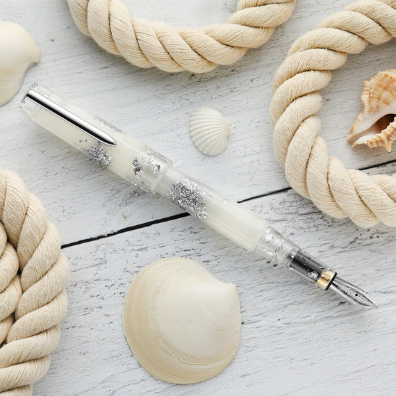 Fountain pen with decorative elements on a wooden surface with ropes and shells.