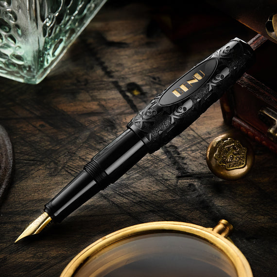 Decorative fountain pen on a wooden surface with a glass and other items.
