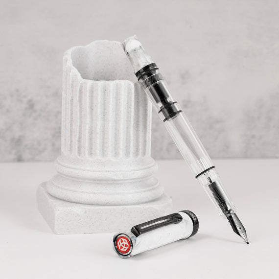Fountain pen with transparent body and white cap on a gray background