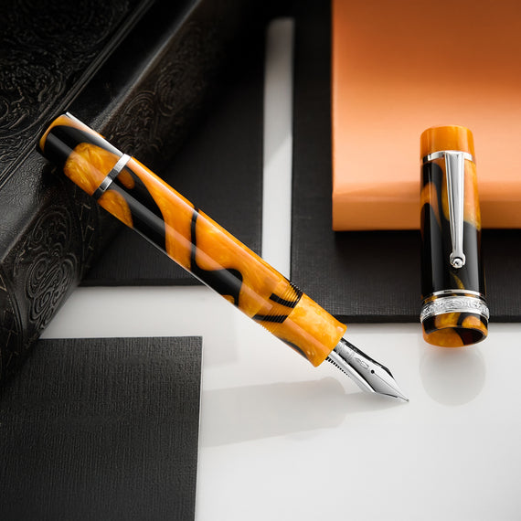 This oversized fountain pen features a marbled black and orange resin barrel and cap with sterling silver trim.