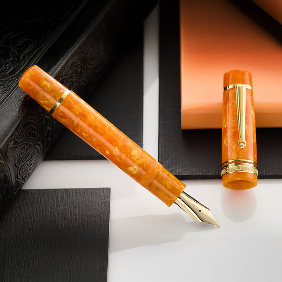 This oversized fountain pen features an orange marbled resin barrel and cap with gold trim.