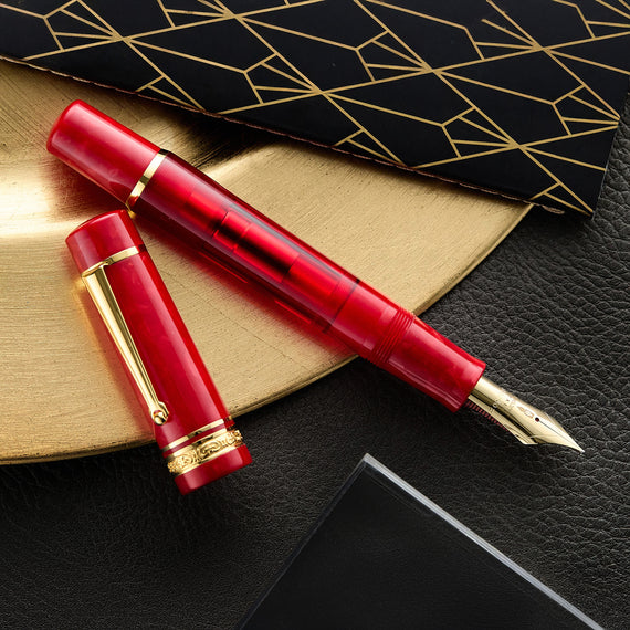 Translucent red fountain pen with gold trim and a decorative gold band on the base of the cap.