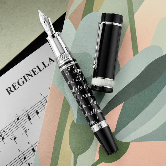 A fountain pen made of hand-turned, special resin in black with white accents and cursive French writing on the barrel.