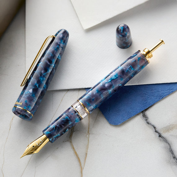 Blue marbled fountain pen with gold accents on a marble surface