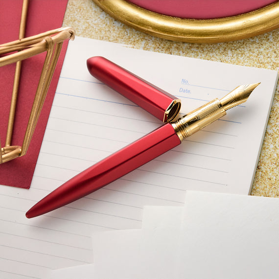 Red and gold pen on a piece of paper with decorative elements in the background