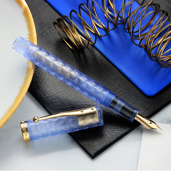 Fountain pen with blue and gold design on a textured surface