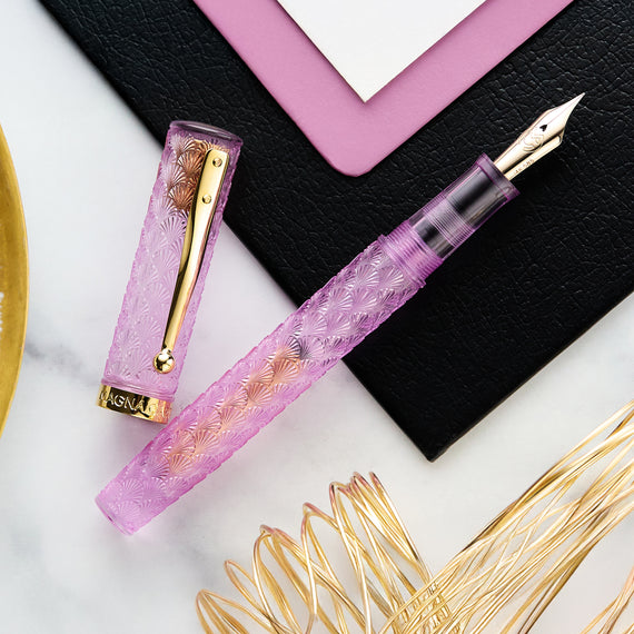 Pink fountain pen with gold accents on a white surface