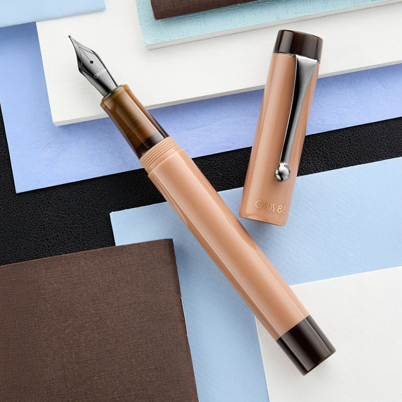 Fountain pen with a beige body and brown accents on a geometric background