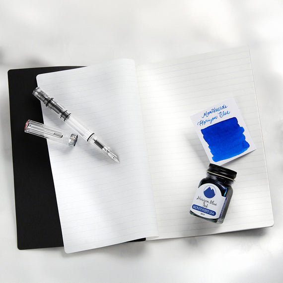 Fountain pen with ink swab and bottle on a white notebook