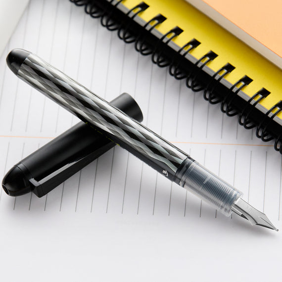 Fountain pen on a piece of paper with a yellow notebook in the background