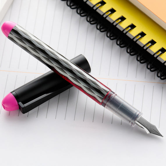 Fountain pen with pink cap and nib on lined paper