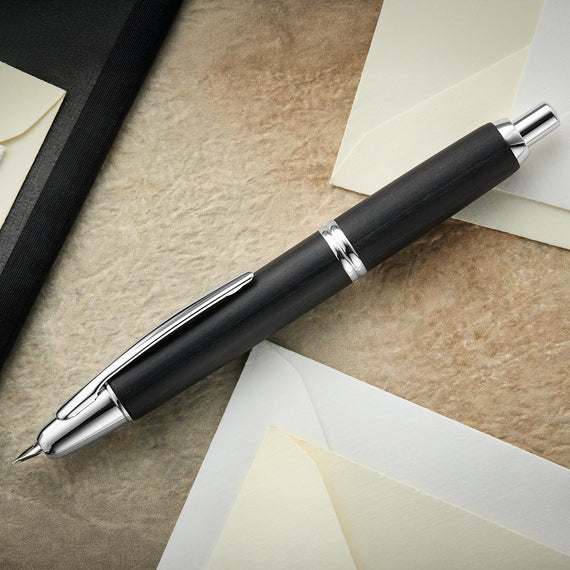 Black pen with silver accents on a textured surface with paper