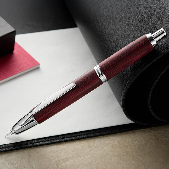 Pen with wooden finish and silver accents on a leather surface