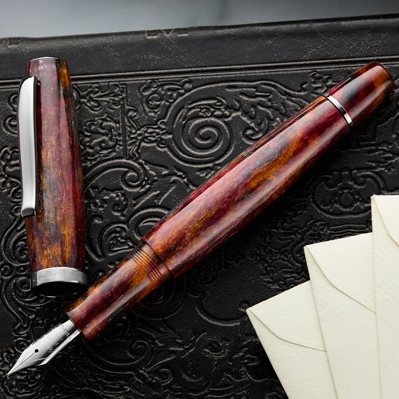 Marbled fountain pen on a textured black surface with an envelope