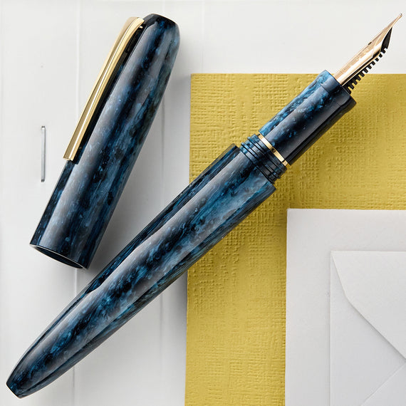 Blue marble-patterned fountain pen with gold accents on a white and yellow background