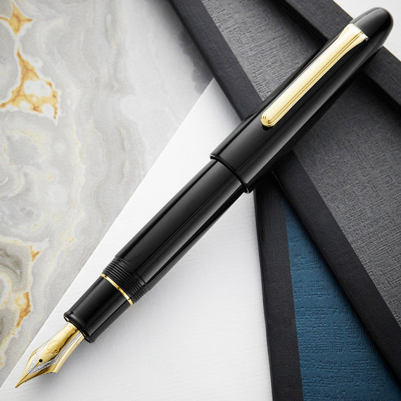 Black fountain pen with gold accents on a marble surface