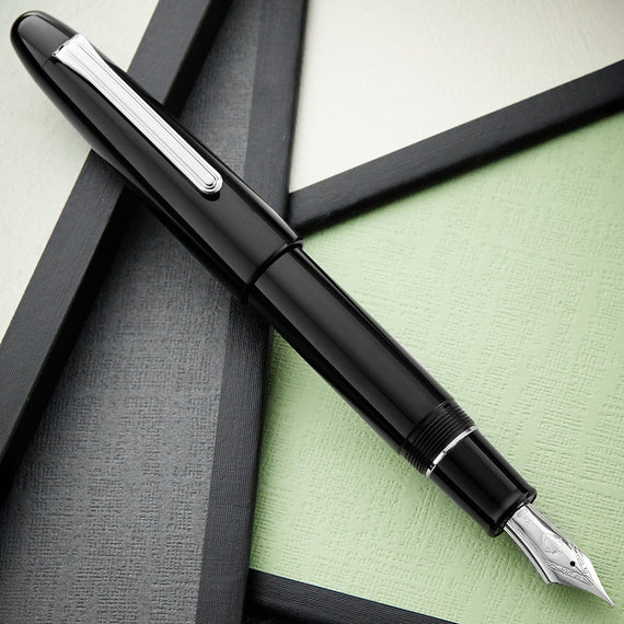 Black fountain pen on a textured surface with a green background