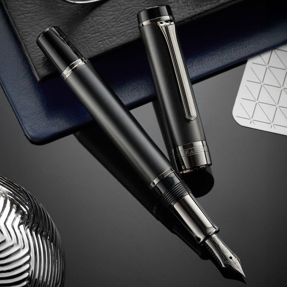 Black fountain pen with silver accents on a dark surface