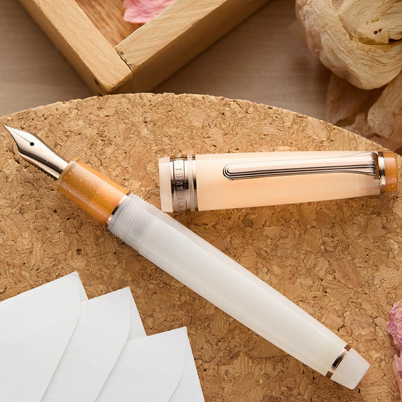 Fountain pen with light orange and white components on a cork surface