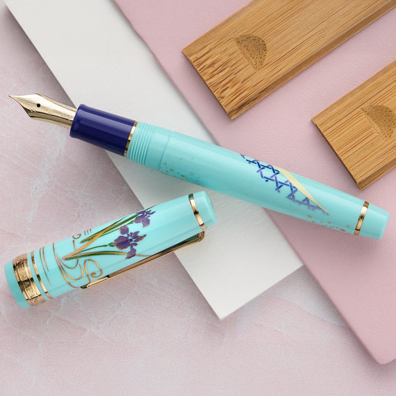 Turquoise fountain pen with floral design on a pink and white background