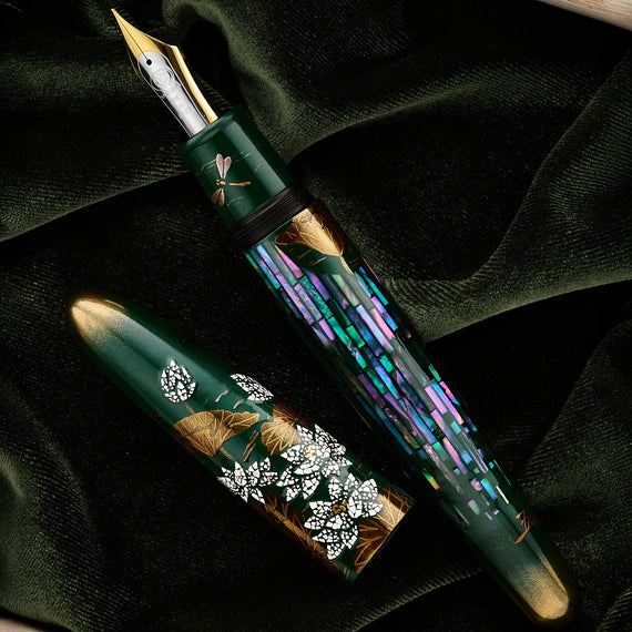 Decorative fountain pen with floral designs on a dark green fabric background