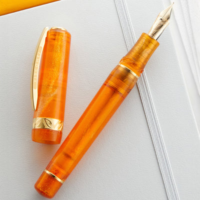 Orange fountain pen with gold accents on a white background