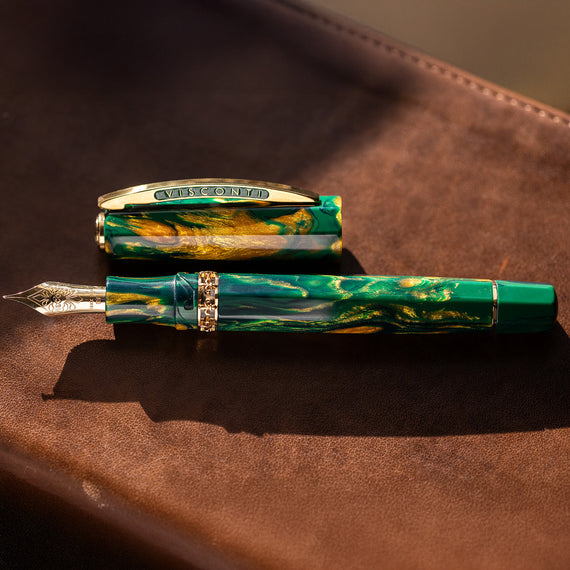Fountain pen with green and gold accents on a brown leather surface
