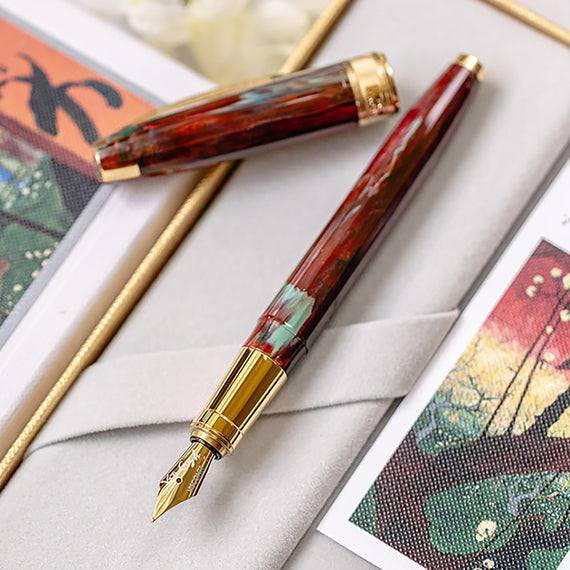 Fountain pen with gold accents on a textured surface with artistic cards.
