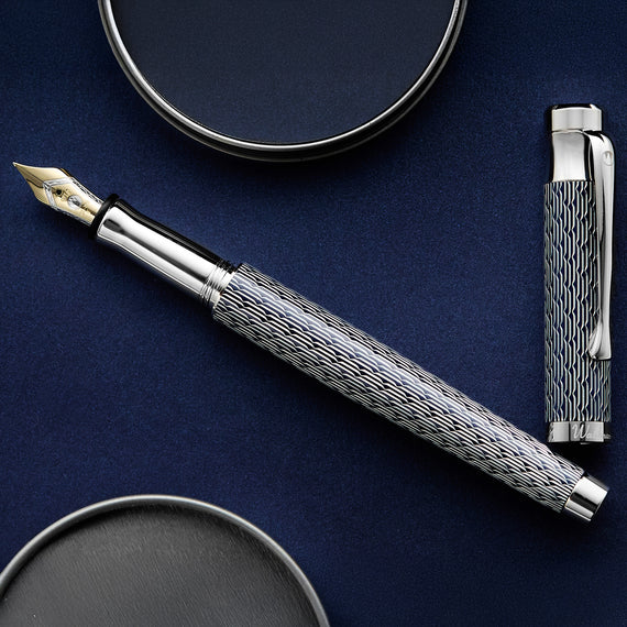 Silver fountain pen with decorative cap on a dark blue background