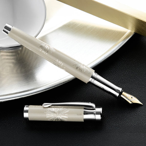 Fountain pen with decorative elements on a dark surface
